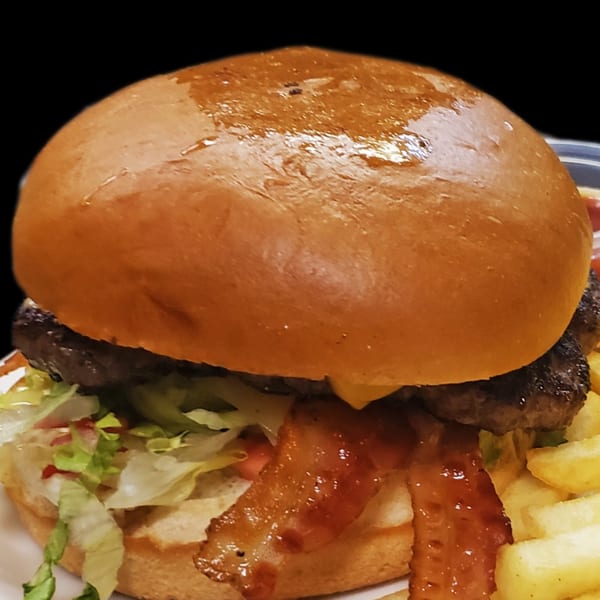 A juicy bacon cheeseburger with lettuce and tomato, served with a side of golden fries.